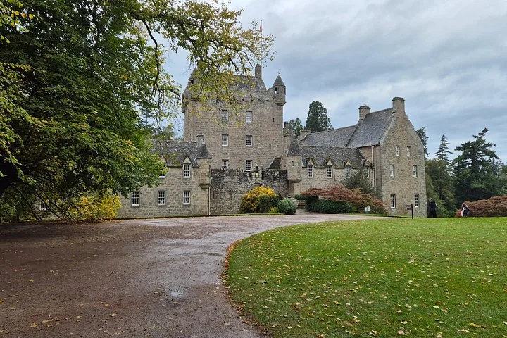A large stone castle with multiple turrets situated on a green lawn.